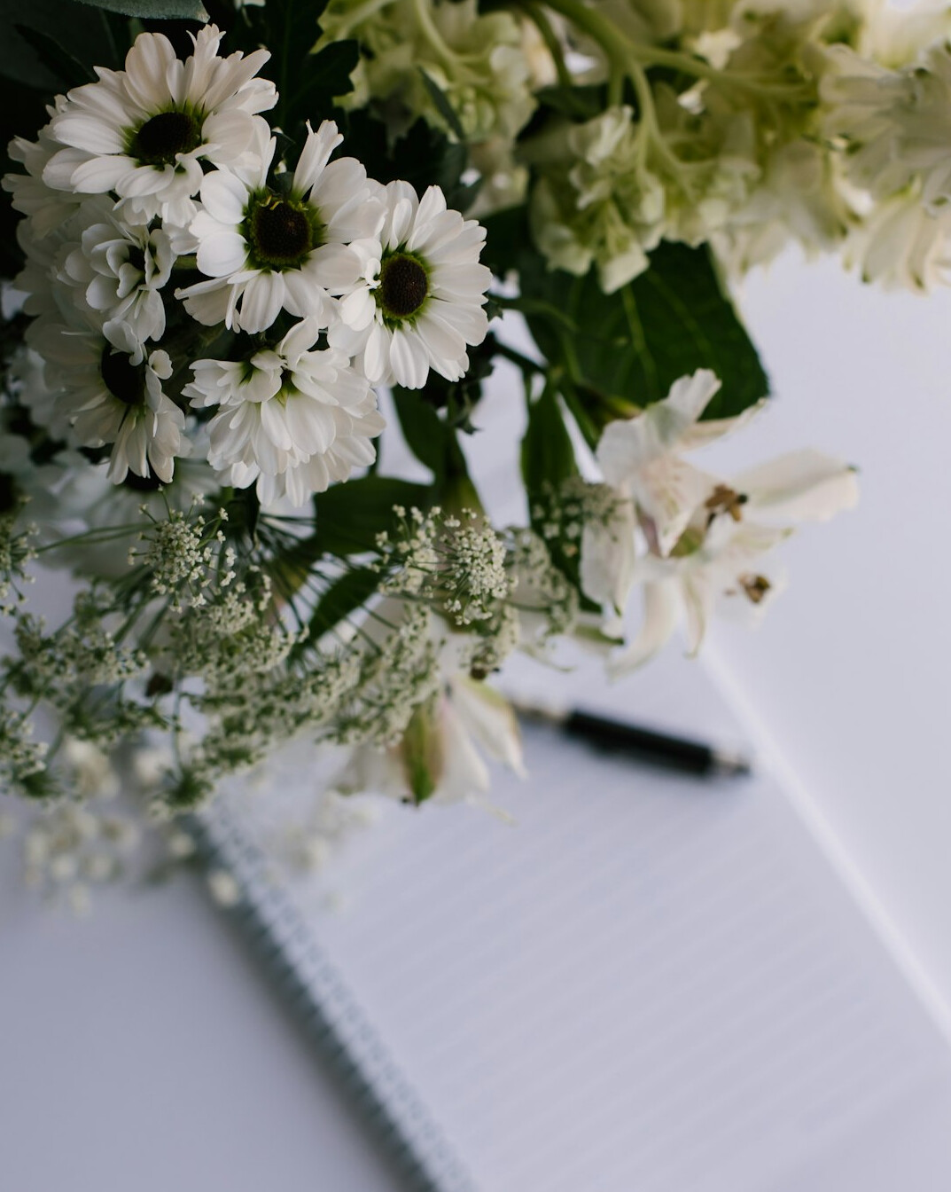 Hand writing notes on paper with a pen at a desk